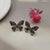Silver-toned or gunmetal butterfly stud earrings.